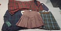 All items laid out: four kilts/skirts, matching blazer, necktie
