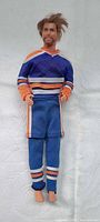 Full view of 12 in Mattel male fashion doll wearing blue/orange Edmonton Oilers uniform, barefoot
