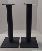 Both speaker stands upright showing overall design, bases and top plates