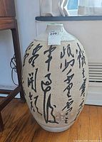 Front view of large speckled earthenware vase with Chinese calligraphy and size reference tag