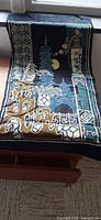 Full view of batik silk scarf laid flat showing pagoda scene and border