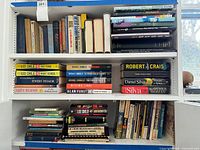 Three shelves filled with assorted hardcover and paperback books
