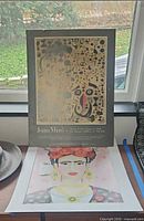 Both prints standing: Miró poster behind Frida print