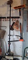 Full view of Poulan Pro PP333 trimmer and orange pole brush hanging on wall