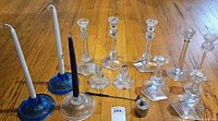 Group of glass candlesticks with candles inserted, stainless burner and snuffer tag visible