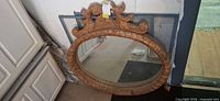 Front view of oval mirror leaning against wall