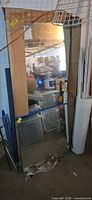 Tall 24x58 frameless mirror in cardboard sleeve leaning in garage