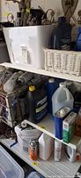 Shelving with assorted spray paint cans, oil bottles, coolant jugs, solvent can, spray bottle