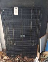 Folded black metal wire pet crate leaning against wall