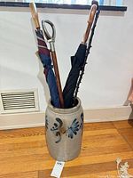 Stoneware crock with two umbrellas and cane inserted