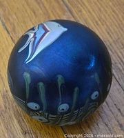 Side view showing fish and seaweed motif on blue iridescent surface