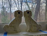 Front view of both Staffordshire spaniel figurines on windowsill