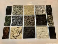 Top view of fifteen polished stone sample tiles arranged in rows showing varied colors and patterns.