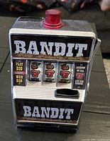 Front view of Bandit novelty slot machine coin bank showing graphics, reels, coin slot and top red light