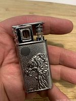 Lighter open showing ignition mechanism and raised headdress skull design