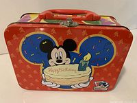 Front of red tin lunchbox showing Mickey with birthday cake