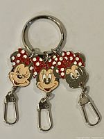 Front view of Disney Minnie Mouse metal enamel keychain showing three charms and detachable clips