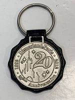 Front view of keychain showing silver medallion with castle, fireworks, years 1992-2012 and wording