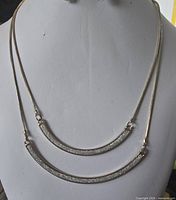 Front view of entire double-layer curved bar necklace on display form