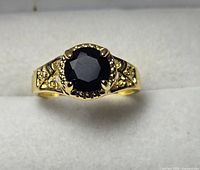 Top view of gold-tone ring with round black faceted center stone