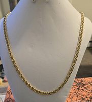 Full view of gold-tone curb chain necklace on display bust
