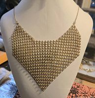 Front view of gold-tone mesh bib necklace displayed on bust