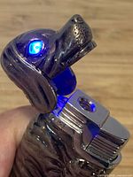 Dog-shaped metal lighter with head open and blue LED lit