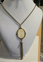 Full view of necklace on bust showing chain, cabochon pendant, and tassel