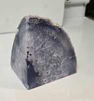 Triangular polished cut geode showing gray-purple quartz crystals with rough outer rind