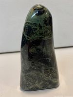 Front view of polished green and black orbicular jasper freeform stone standing upright