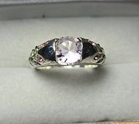 Front view of silver-tone ring showing pale pink faceted center stone and band detail