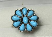 Top view of silver-tone ring showing flower cluster design with blue cabochons
