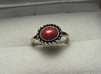 Top view of silver-tone ring with red cabochon in rope-twist bezel