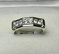 Front view showing six round clear stones channel-set in rectangular top of silver-tone ring with gold-tone edge