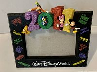 Front view of frame showing glitter 2011 topper, character figures, attraction logos, and photo opening