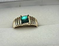 Top view of ring showing green faceted stone and ribbed gold-tone band