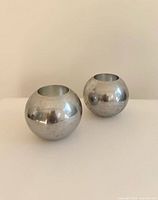Two polished spherical metal candle holders front view