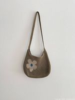 Front view showing brown crochet bag with flower design and strap