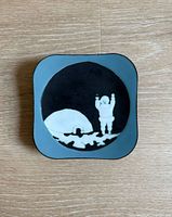 Front view of enamel plaque showing igloo and figure scene