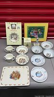 Group shot of all Bunnykins dinnerware, figurine, boxes and framed print