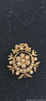 Front view of yellow gold circular brooch with seed pearls