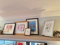 Group of five assorted frames on shelf
