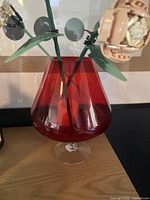 Red glass vase with clear foot on wooden surface
