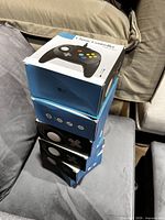 Stack of five blue and white Classic Controller boxes on sofa