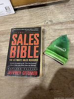 Front view of paperback book and green TradeRev pouch on wood surface