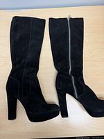 Left and right black suede knee-high boots lying flat, side profile shown