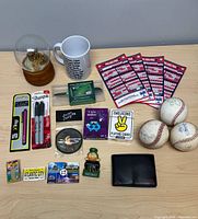 Overview of all items on tabletop: baseballs, mug, snow globe, pocket schedules, markers, stylus pens, playing cards, wallet, magnets, CD/DVD, gift card sleeve