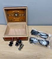 Open Perdomo cigar box, metal couplers, two bagged sunglasses