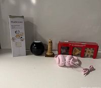 All five items lined up: Radezon aerator box, Magic 8 Ball, Pisa tower, wooden puzzles box, pink headphones