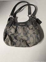 Full view of Coach Signature handbag showing exterior pattern, handles and hangtag